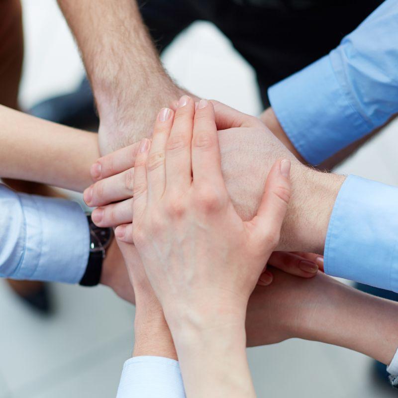 Equipo de trabajo uniendo sus manos en señal de unidad y colaboración sindical